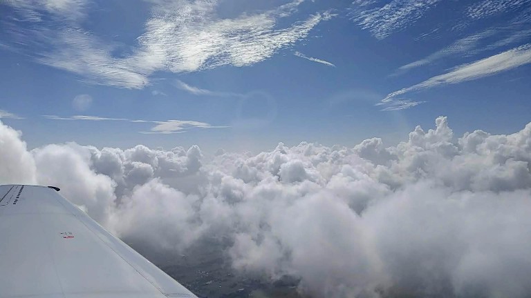 blue skies and fluffy white clouds from the window seat of an airplane