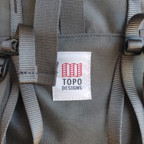 Topo Designs white tag on charcoal background of the Mountain Pack
