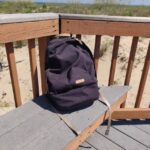 Bellroy Classic Backpack (front side) in black dura nylon perched on a beach house deck