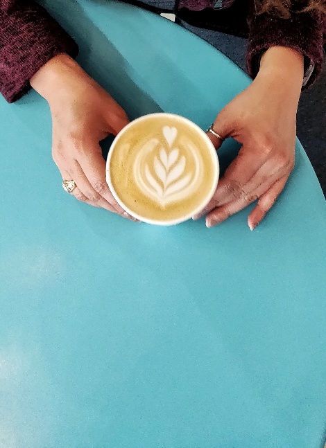 Ladies handles cradling a coffee cup featuring latte art