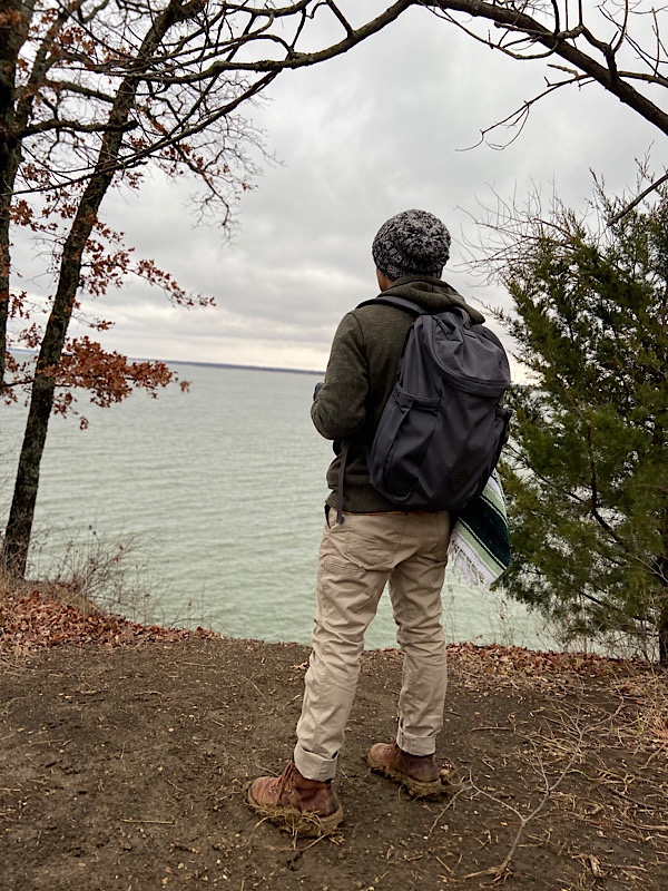 Man in winter gear wearing Millican Oli The Zip overlooking lake