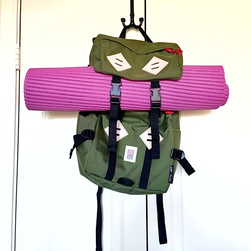 rolled-up yoga mat strapped to backpack