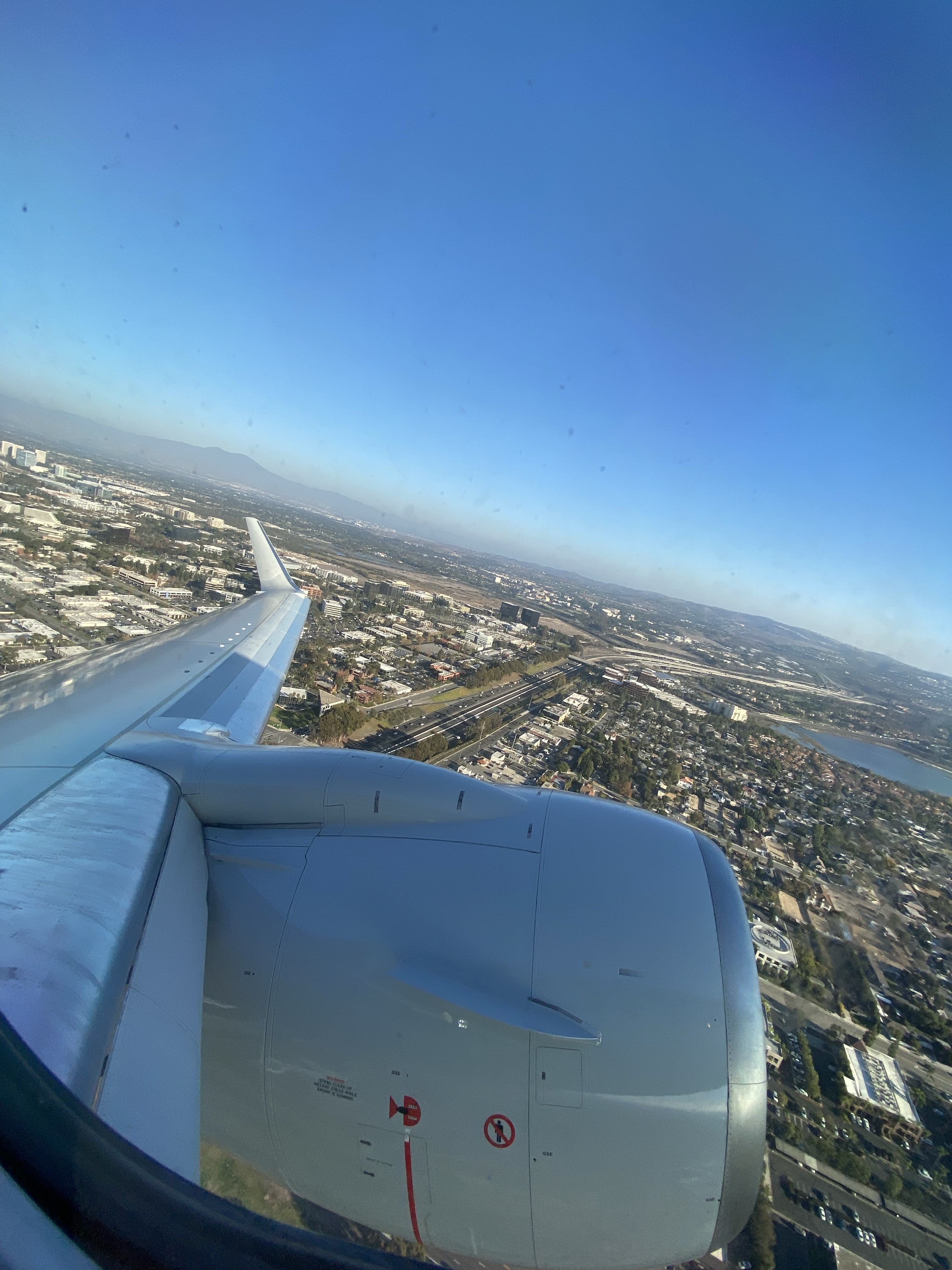 view of an airplane engine & wing from the cabin during takeoff on a sunny day
